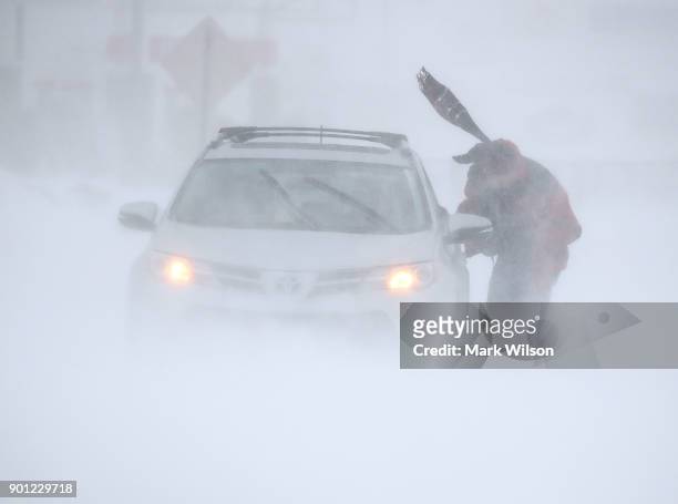 Man tries to get his car unstuck in near white out conditions as a storm passes, on January 4, 2018 in Rehoboth Beach, Delaware. A winter storm is...
