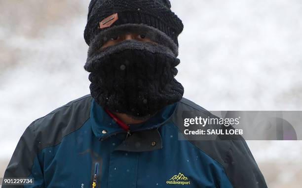 Man covers his face as he visits the Lincoln Memorial on the National Mall during a snow storm in Washington, DC, January 4, 2018. A giant winter...