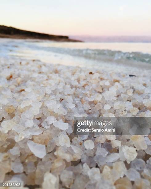 close up of grains of salt on the jordanian shore of the dead sea at sunrise - totes meer stock-fotos und bilder