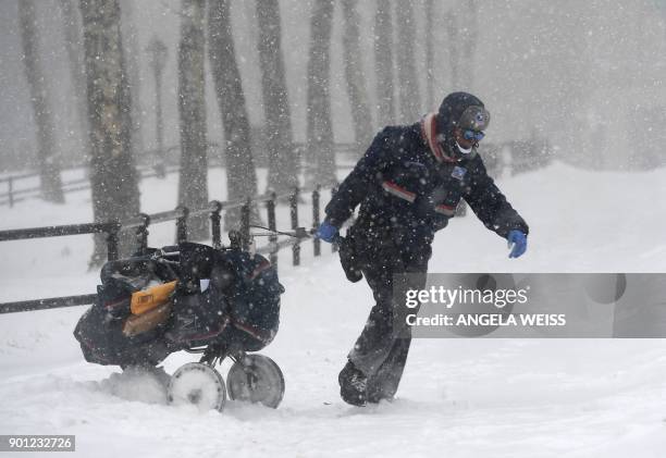Mail delivery person pulls her cart through the snow on January 4, 2018 in Brooklyn, New York. A giant winter "bomb cyclone" walloped the US East...