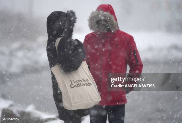 Couple stands in the snow on January 4, 2018 in Brooklyn, New York. A giant winter "bomb cyclone" walloped the US East Coast on Thursday with...