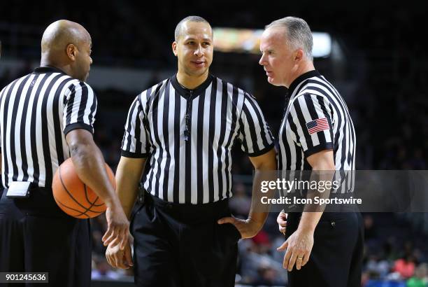 From left to right, referees Jeffrey Anderson, Matt Potter and John Gaffney huddle during a college basketball game between Marquette Golden Eagles...
