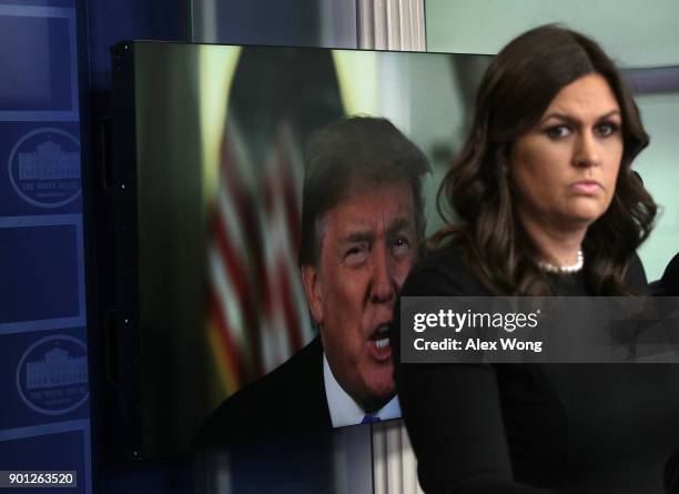 President Donald Trump speaks via a video as White House Press Secretary Sarah Sanders listens during a daily news briefing at the James Brady Press...