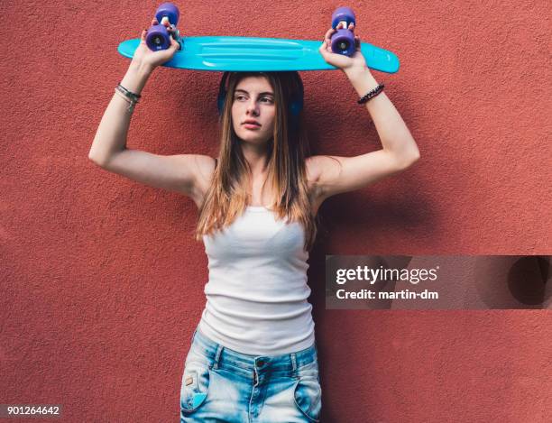 skate girl standing against red wall - mind over matter stock pictures, royalty-free photos & images