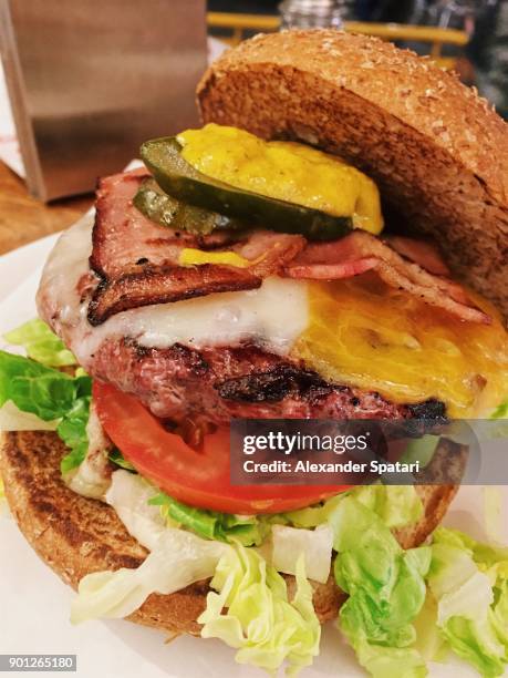 close up of a big juicy burger with bacon, cheese and pickles - pickled pork stock pictures, royalty-free photos & images