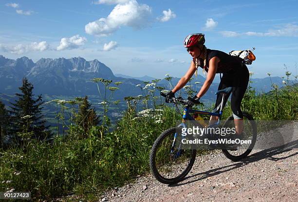 Female mountainbiker cycling down the Hahnenkamm with a view on the Kaisergebirge on August 16, 2009 in Kitzbuhel, Austria. Kitzbuehel is famous for...