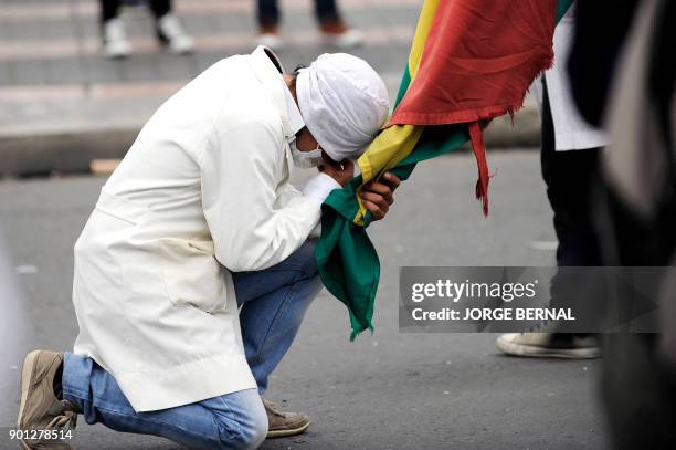 Medicine student kneels holding a Bolivian national flag, amid a protest against a new law that penalizes medical malpractice, near the Health...