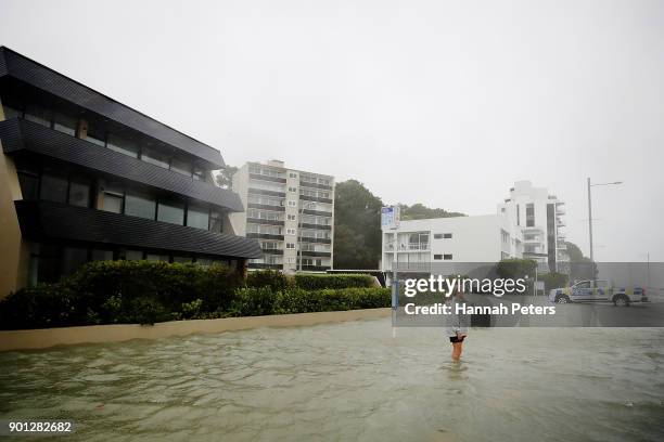 Walker stands on the flooded waterfront on January 5, 2018 in Auckland, New Zealand. Heavy wind and rain have struck the region, with over 12,000...