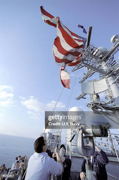 Signalman aboard USS John C. Stennis hoists a 12 x 18 foot flag, which was found in the rubble of the World Trade Center and sent to the carrier for...