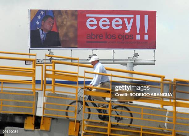 Man rides his bike near a billboard with a picture of Ecuadorean President Rafael Correa and a slogan reading "Hey, Open Yor Eyes" , in Bogota, on...
