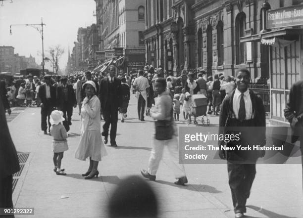 Busy street in Harlem, New York, New York, 1929. 'Free Milk Fund for Babies' at right. Possibly Lenox Avenue, looking south from just south of 130th...