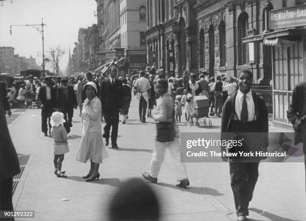 Busy street in Harlem, New York, New York, 1929. 'Free Milk Fund for Babies' at right. Possibly Lenox Avenue, looking south from just south of 130th...