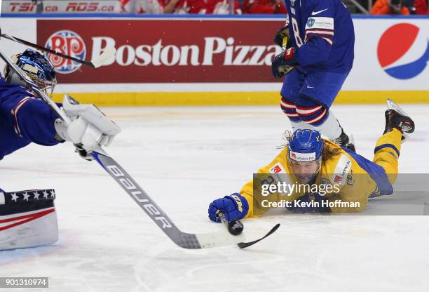 Joseph Woll of United States pokes the puck away from Axel Jonsson Fjllby of Sweden in the third period during the IIHF World Junior Championship at...
