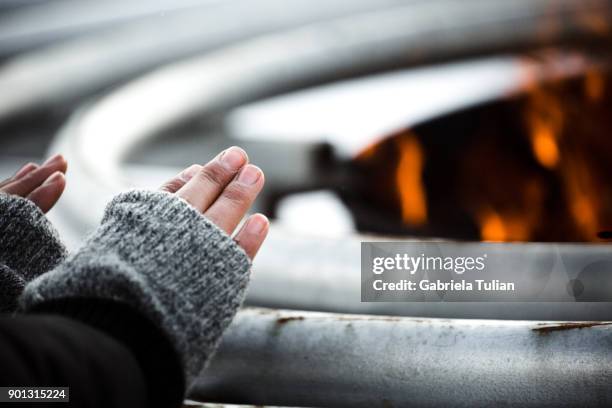 girl is warming hands in gloves over the fire - navidad ストックフォトと画像