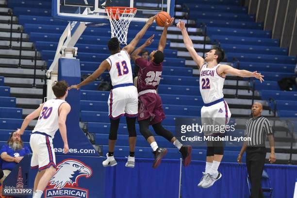 Marvin Bragg of and Sam Iorio of the American University Eagles block the shot of Jordan Robertson of the Colgate Raiders during a college basketball...