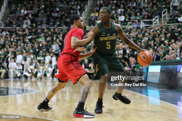 Cassius Winston of the Michigan State Spartans handles the ball defended by Anthony Cowan Jr. #1 of the Maryland Terrapins at Breslin Center on...