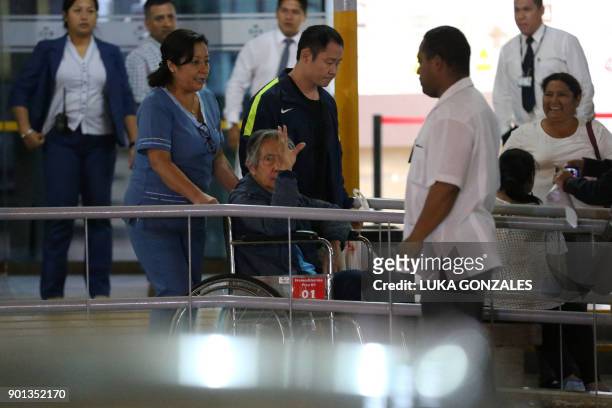 Peru's former President Alberto Fujimori waves to supporters as he is wheeled out of the Centenario Clinic in Lima on January 04 where he was...
