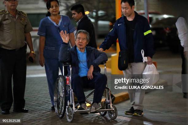 Peru's former President Alberto Fujimori waves to supporters as he is wheeled out of the Centenario Clinic in Lima on January 04 where he was...