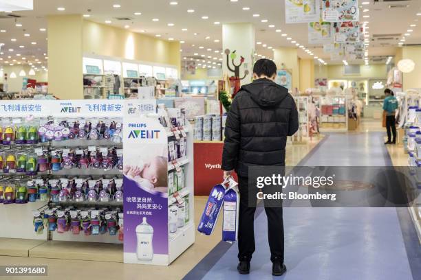 Customer stands next to an advertisement for Royal Philips NV's Avent brand inside a Shanghai Aiyingshi Co. Babemax store in Shanghai, China, on...