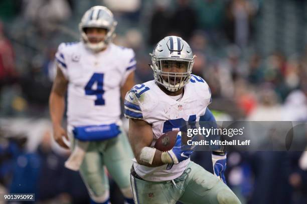 Ezekiel Elliott of the Dallas Cowboys runs the ball as Dak Prescott looks on against the Philadelphia Eagles at Lincoln Financial Field on December...