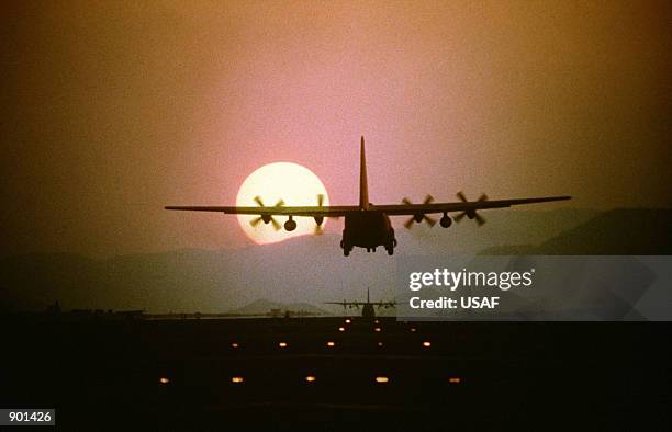 Silhouetted by the setting sun, a C-130 Hercules aircraft prepares to land during a 10-ship air drop exercise being conducted by the 21st Tactical...