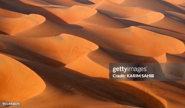 An Emirati man walks with a camel in the Liwa desert, some 250 kilometres west of the Gulf Emirate of Abu Dhabi, during the Liwa 2018 Moreeb Dune...