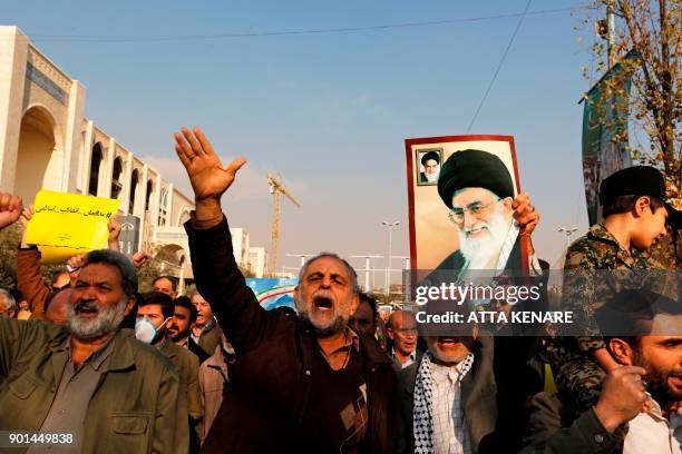 Pro-government demonstrators hold a poster of Iran's supreme leader, Ayatollah Ali Khamenei and Iran's founder of Islamic Republic, Ayatollah...