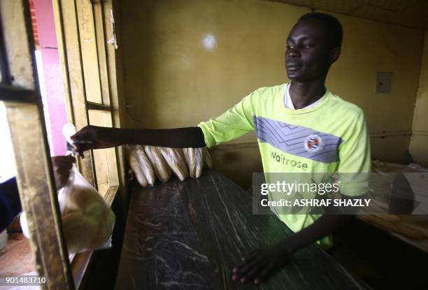 Sudanese man hands a bag of bread to a costumer at a bakery in the capital Khartoum on January 5, 2018. Angry Sudanese queued outside bakeries in...