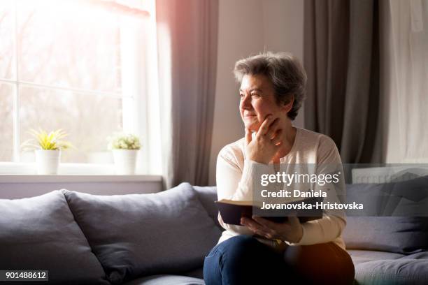 ältere frau mit bibel - women prayer stock-fotos und bilder