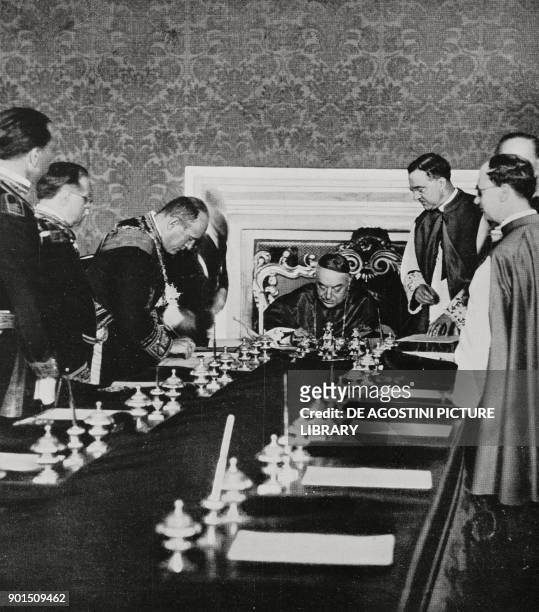 Benito Mussolini and Cardinal Pietro Gasparri signing the ratification of the Lateran Pacts in the Hall of Congregations at the Vatican, June 7 from...