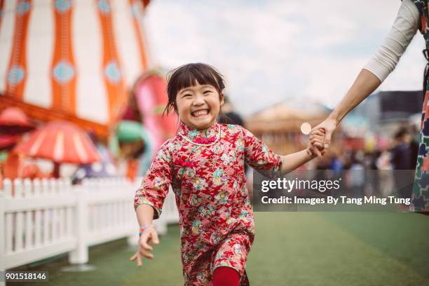 lovely little daughter holding mom's hand running in a carnival joyfully. - carnival celebration event 個照片及圖片檔