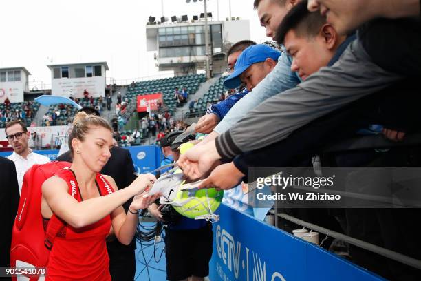 Simona Halep of Romania signs autographs for fans after winning her semi-final match against Irina-Camelia Begu of Romania on Day 6 of 2018 WTA...