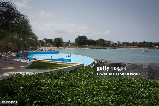 People enjoy the infinity pool at te Pestana hotel and resort in Sao Tome city on January 2, 2018. - Tourists to Sao Tome and Principe, a scattering...