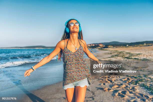 cheerful young woman listening music on beach - bulgaria beach stock pictures, royalty-free photos & images