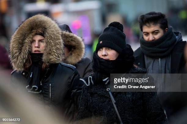 Bundled up pedestrians walk through Times Square, January 5, 2018 in New York City. Brutally cold temperatures and wind chills are expected in the...