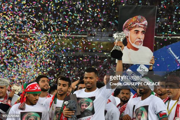 Oman's goalkeeper Fayez Issa al-Rusheidi holds the trophy next to his teammates after his team won the Gulf Cup of Nations 2017 final football match...