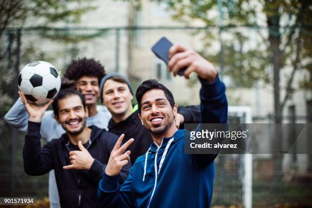 smiling players taking selfie through mobile phone - young men group stock pictures, royalty-free photos & images