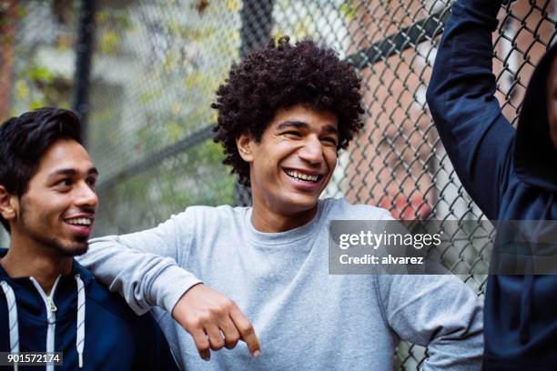 Happy players looking away while standing by fence