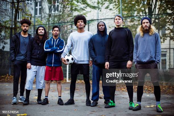 confident soccer players standing against fence - street football stock pictures, royalty-free photos & images