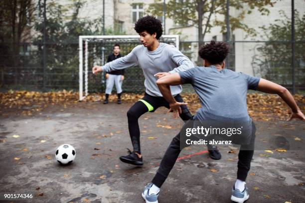 soccer players tackling and defending in match - street football stock pictures, royalty-free photos & images