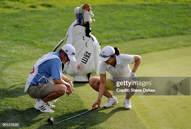 Candie Kung of Taiwan and her caddy Jeff King measure for relief under a special rule for the step cut rough on the 18th hole during the first during...