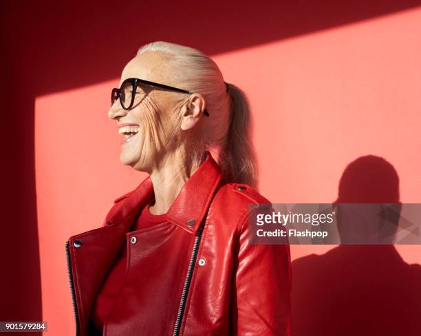 portrait of mature woman laughing - red coat foto e immagini stock