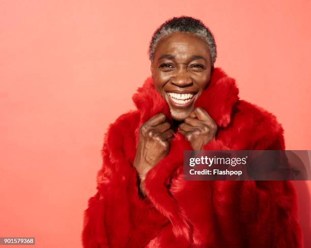 portrait of mature woman laughing - roter mantel stock-fotos und bilder