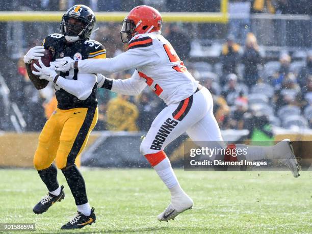 Running back Fitzgerald Toussaint of the Pittsburgh Steelers catches a pass as he is tackled by linebacker James Burgess Jr. #52 of the Cleveland...