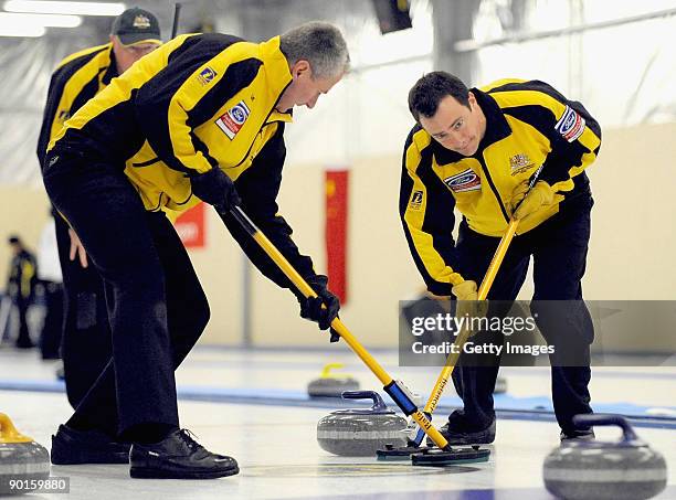 John Theriault and Steve Johns of Australia sweep team mate Hugh Millikin's stone during the Men's Curling Final on day eight of the Winter Games NZ...