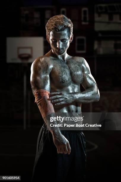 man in a local basketball court holding his elbow where there has been an injury - elastic bandage stockfoto's en -beelden