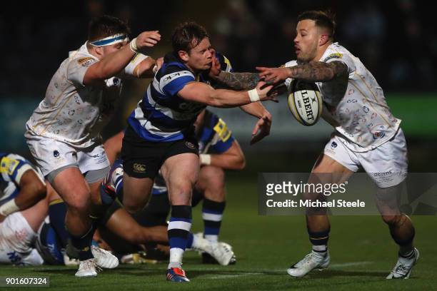 Chris Cook of Bath offloads as he is tackled by Francois Hougaard and GJ van Velze of Worcester during the Aviva Premiership match between Worcester...