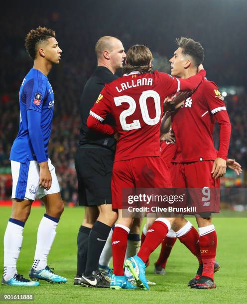 Referee Robert Madley and Adam Lallana of Liverpool intervene as Mason Holgate of Everton and Roberto Firmino of Liverpool clash during the Emirates...