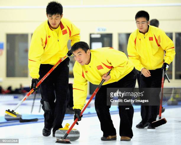 Chinese curlers Xu Xiaoming and Li Hongchen sweep team mate Zang Jialiang's stone during the Men's Curling Final on day eight of the Winter Games NZ...