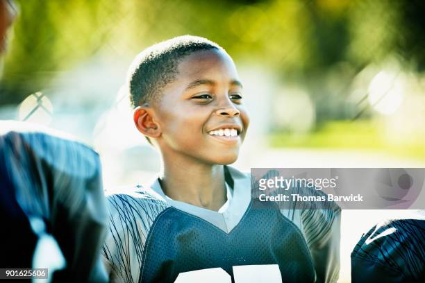 smiling young football player standing with teammates after football game - american football uniform stock pictures, royalty-free photos & images
